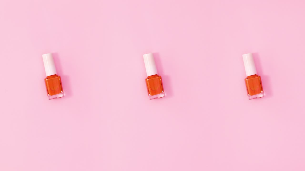 tres botellas de esmalte de uñas giran sobre un fondo rosa pastel. detenga el movimiento