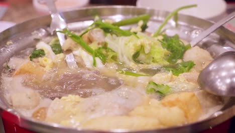 Detail of chopsticks removing vegetables from a boiling sukiyaki pot