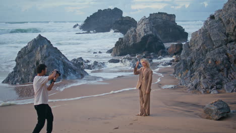 man professional shooting model on ocean beach. shore girl in suit posing camera