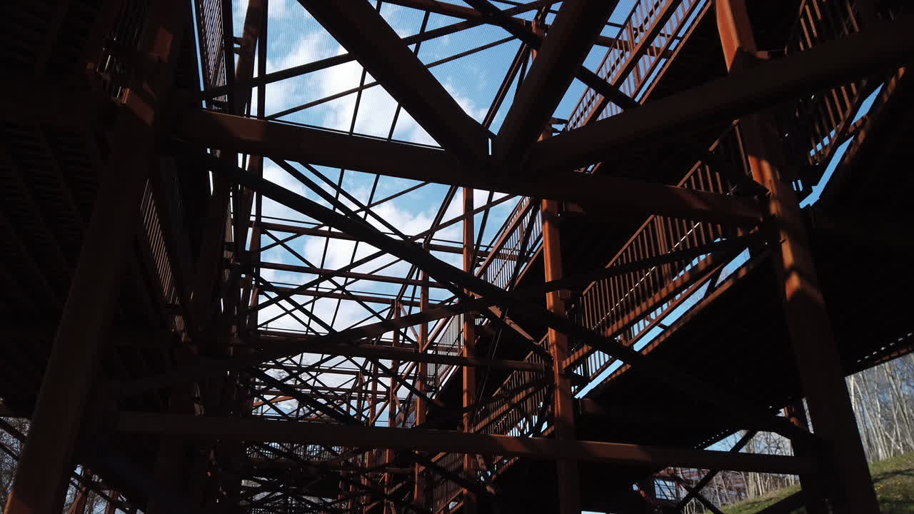 View of the intricate structure and interconnected beams on a newly built walking bridge, low angle wide shot with tilt down