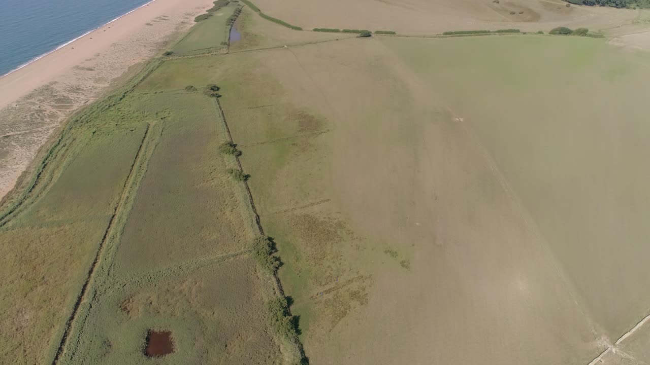 vista aérea desde arriba sobre una laguna avanza y se eleva para revelar la playa de chesil, dorset