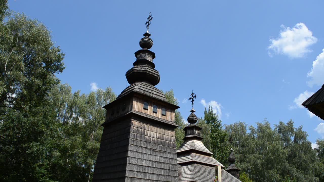 Gökyüzü ve orman fonunda Rum Katolik kilisesi. Yakınlardaki bir köyden taşınarak "Şevçenko Guy" halk mimarisi müzesine yeniden kurulan eski bir ahşap Ortodoks kilisesi. Lviv, Ukrayna