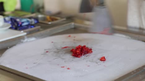 Preparation-of-a-stir-fried-ice-cream,-rolled-ice-cream,-with-chopped-strawberries-and-milk-over-a-freezing-cold-stainless-steel-surface