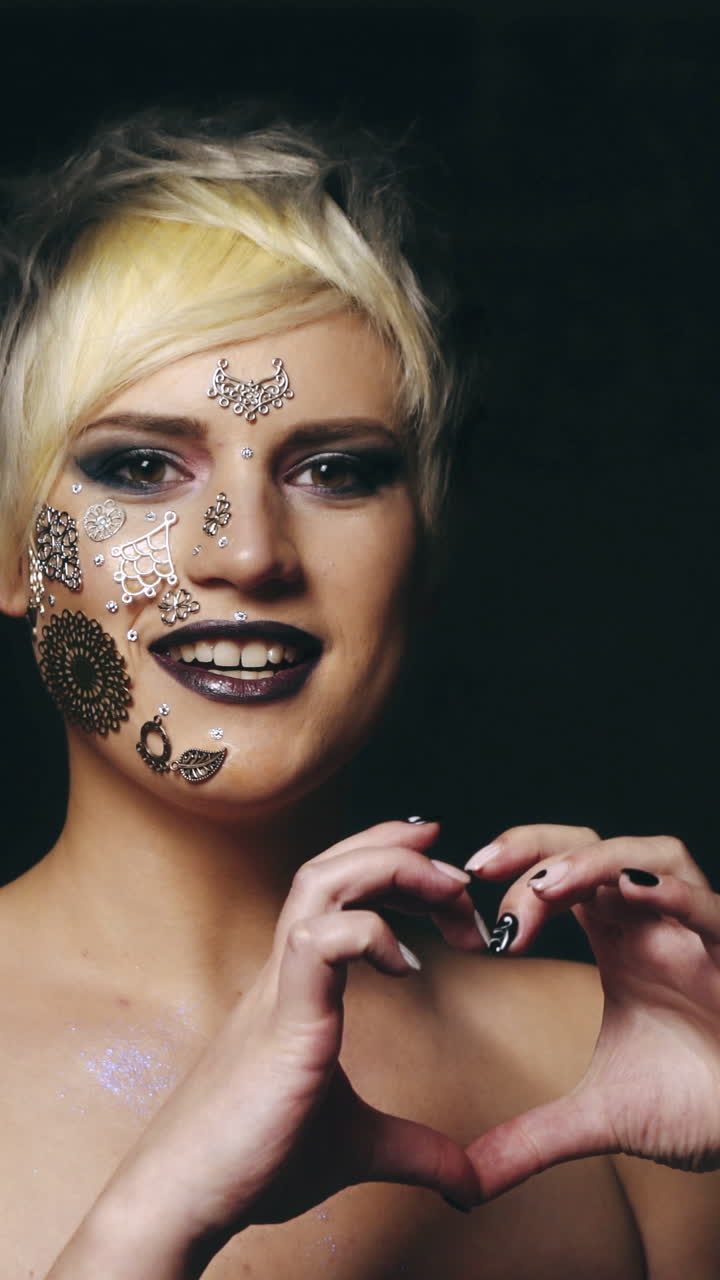 Woman showing heart shaped hands. Young attractive woman in black studio showing heart shaped hands