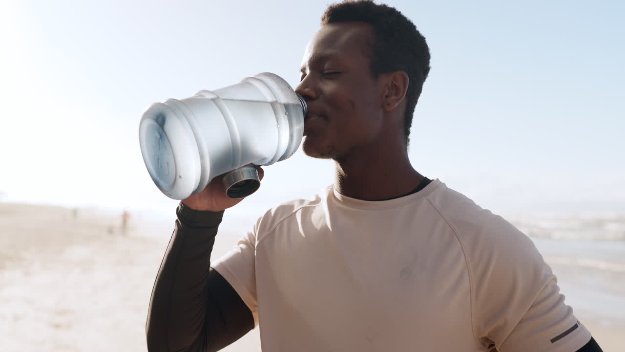 hombre negro, fitness y agua potable en la playa