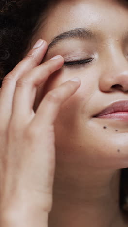 vertical video of biracial woman with dark hair touching her face, slow motion