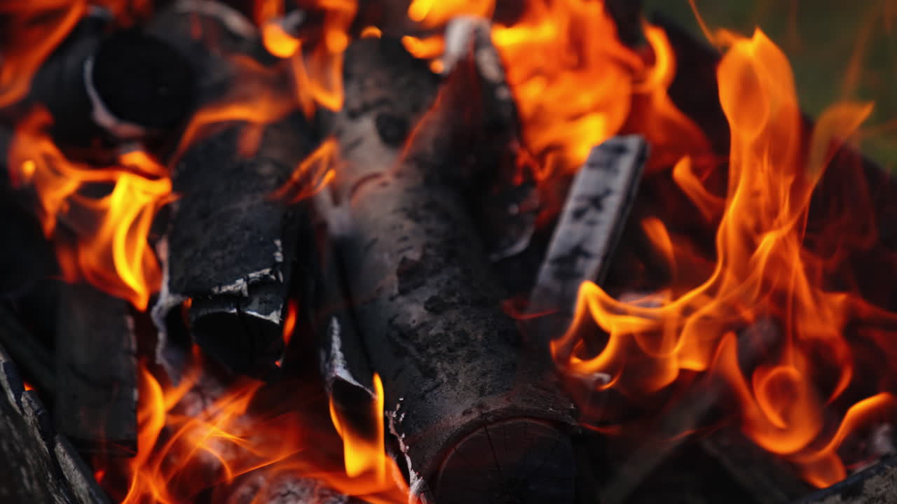 Coals are burning in fire flame. Orange fire transforms the wood into charcoal in the grill. Background of burning logs. Close-up