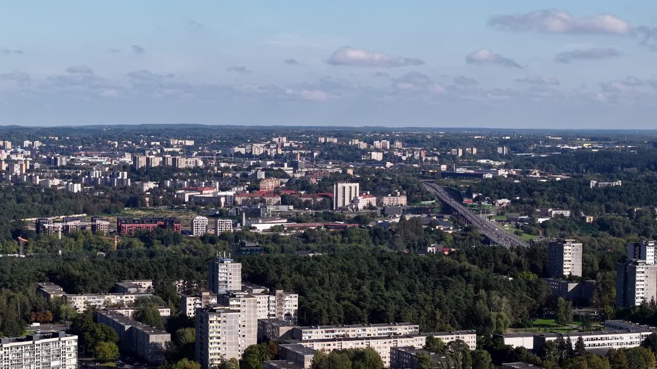 Boczny widok z drona na budynki mieszkalne w Lazdynai, obszary leśne i drogę główną