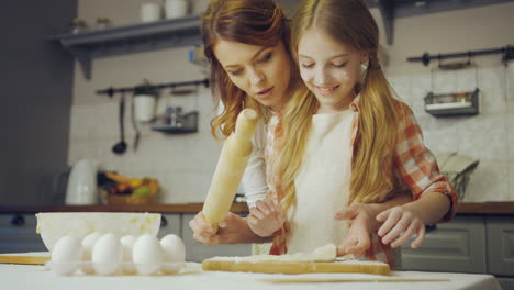 retrato de la madre enseñando a su hija a hacer una hija en la mesa en la cocina moderna. interior