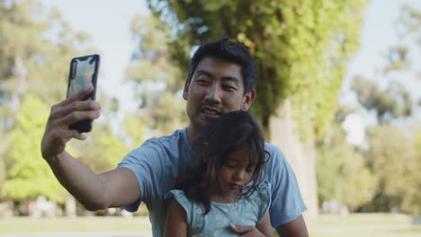 Glücklicher-Asiatischer-Junger-Vater,-Der-Selfie-Mit-Tochter-Im-Park-Draußen-Macht