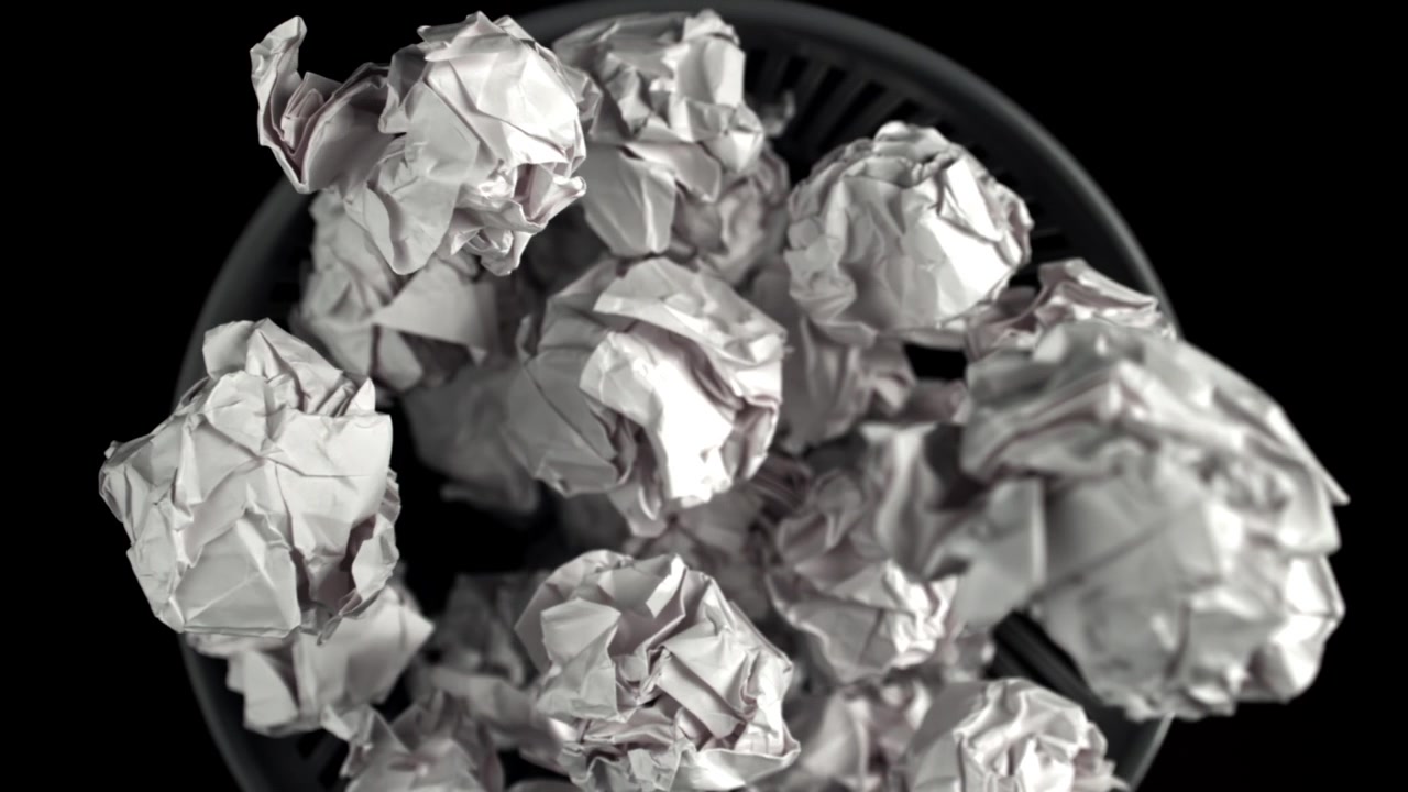 Papelera desbordándose con papeles blancos arrugados