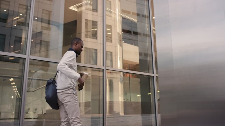Empresário afro-americano caminhando pela cidade usando smartphone