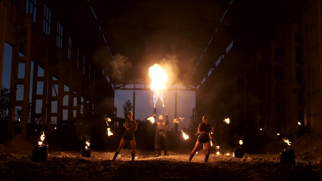 A group of professional artists with fire show the show juggling and dancing with fire in slow motion.