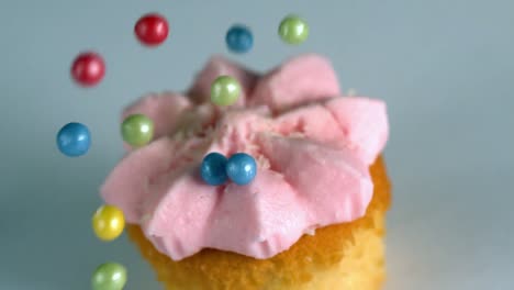 sugar balls falling onto cupcake with pink frosting