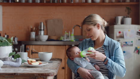 young mother feeding unhappy baby drinking from milk bottle crying restless infant at home with tired mom