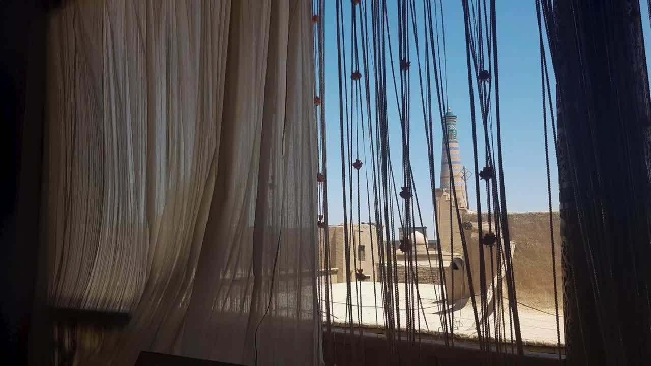 cortinas orientales en una ventana con vista a la antigua ciudad amurallada de khiva, uzbekistán
