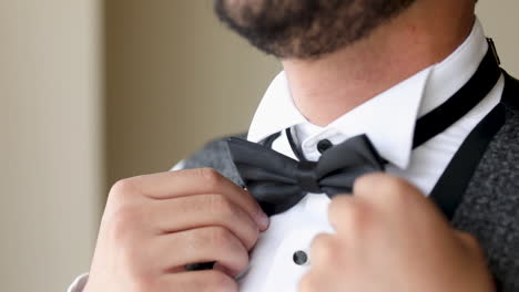 The-groom-adjusts-His-black-bow-Tie---close-up