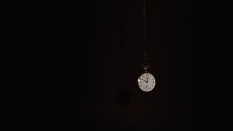 pocket watch swings on a dark background