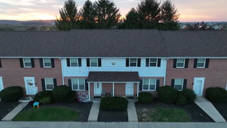 Twilight-over-a-townhouse-complex-with-a-shingled-roof-and-parked-cars