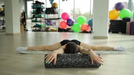 mujer estirándose con un rodillo de espuma en el gimnasio