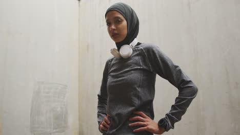 mujer en ropa deportiva con auriculares inalámbricos usando hijab