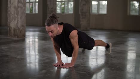 hombre adulto musculoso trabajando en un estudio de loft haciendo flexiones de mano cerrada. hombre modelo de buen aspecto con rastas haciendo ejercicio en el loft. concepto de bienestar, calistenia, aeróbicos, estilo de vida saludable, bienestar
