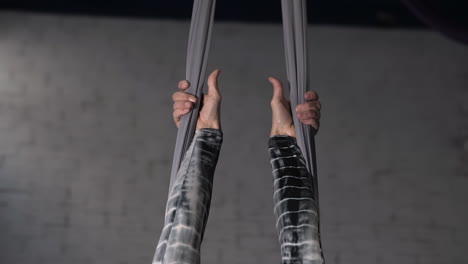 cerca de las manos de una fuerte gimnasta sosteniendo las cuerdas antes de un ejercicio acrobático