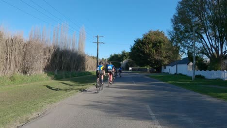 Los-Ciclistas-De-Carreras-Compiten-En-Un-Evento-Que-Pasa-A-Través-De-Largas-Sombras-De-Mediados-De-Invierno---Old-Tai-Tapu-Road,-Canterbury