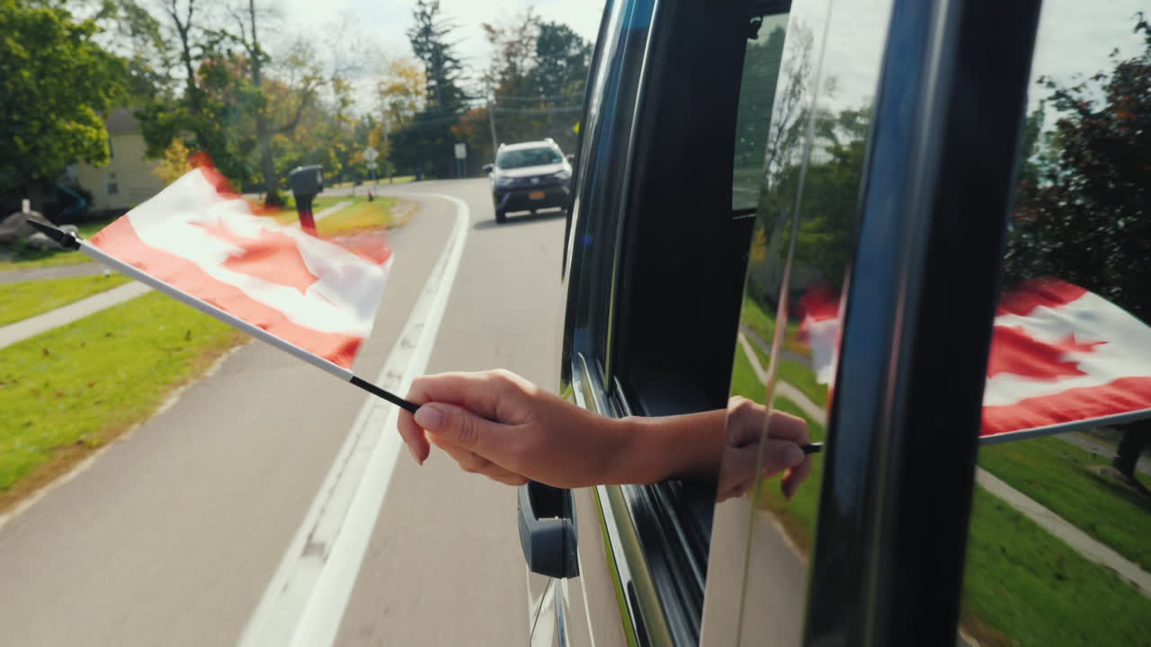 mano sujetando la bandera de canadá fuera de la ventana del coche