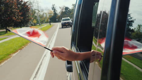 Hand-Holding-Canada-Flag-Out-of-Car-Window