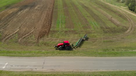 farmer on a tractor turns around near the road and begins plowing farmland in spring in sunny weather