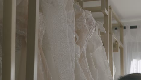a close-up shot of detailed lace bridal gowns hanging in a boutique, exuding elegance. soft, natural lighting enhances the delicate textures and intricate design