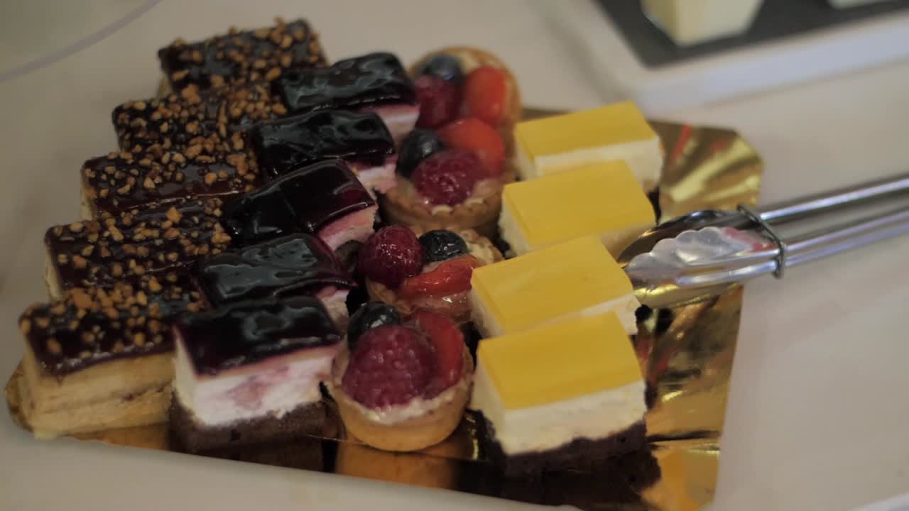 Handheld shot of colourful mini desserts and pastries neatly arranged for serving.
