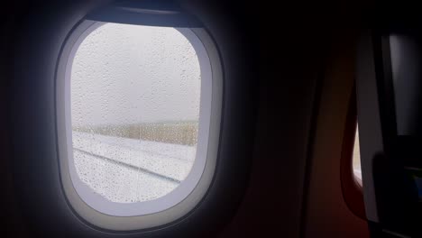 raindrops on an airplane window with a misty view of the runway in greece