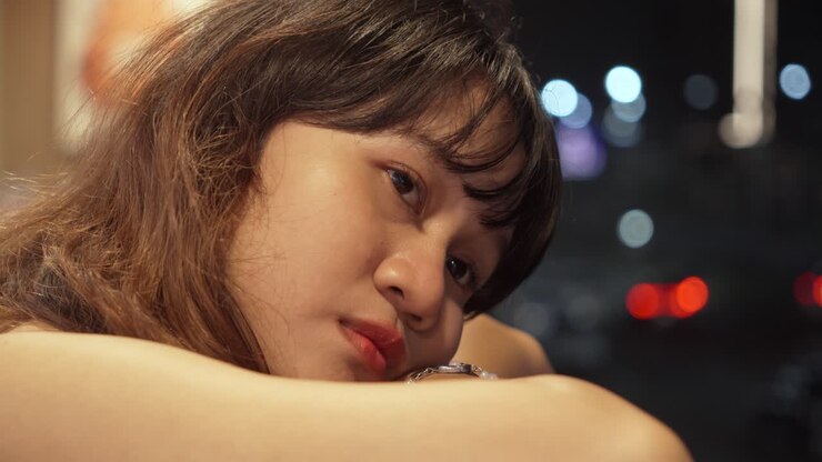 Young Southeast Asian Woman Looking Out The Balcony Window With Sad Longing Eyes.