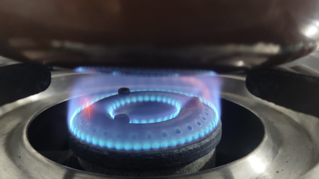 Close-up of blue gas flame burning on kitchen stove, showing clean energy and cooking heat in action. Ideal for energy, culinary and kitchen-themed stock footage in 4K.