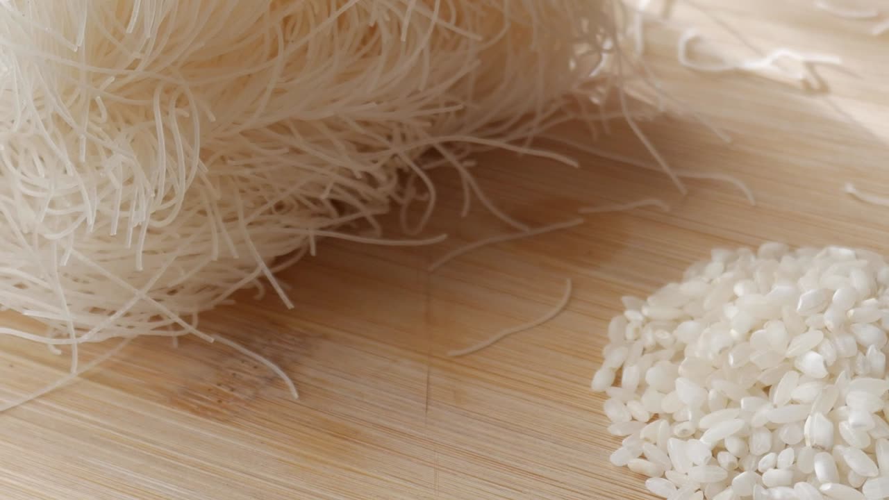 White rice next to thin vermicelli noodles on a wooden cutting board