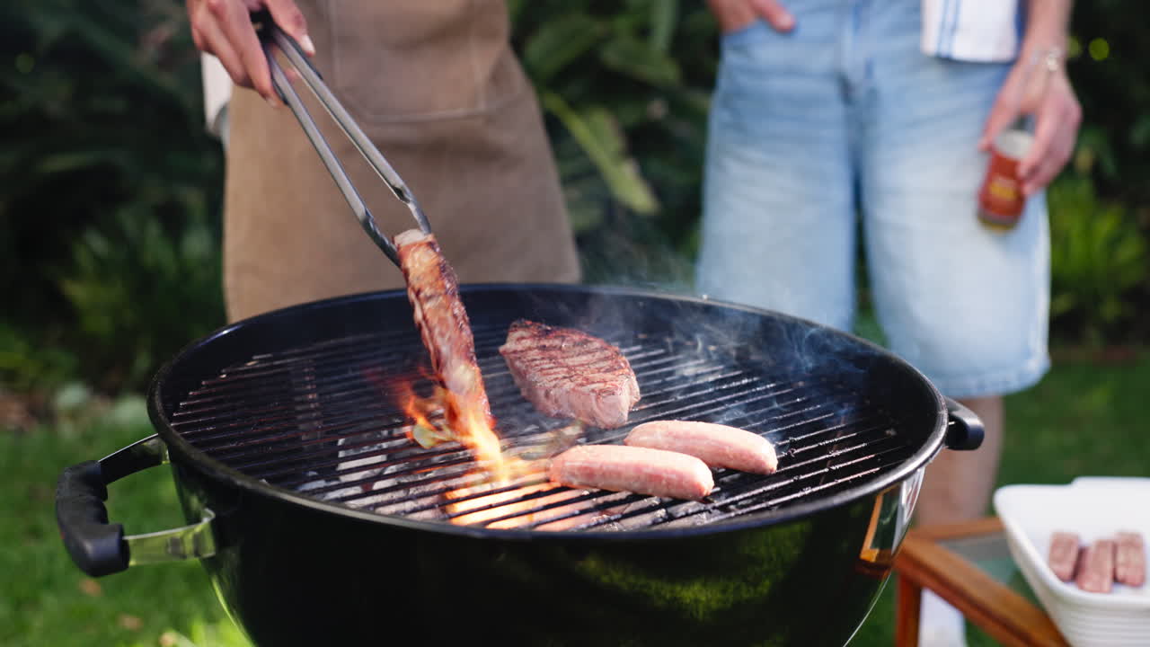 Seseorang Memanggang Steak dan Sosis di Barbecue di Halaman Belakang