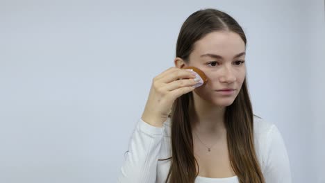 Confused-young-Caucasian-brunete-woman-made-a-mistake-applying-wrong-makeup-in-front-of-the-mirror-white-background