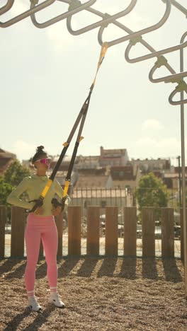 woman working out outdoors with suspension trainer