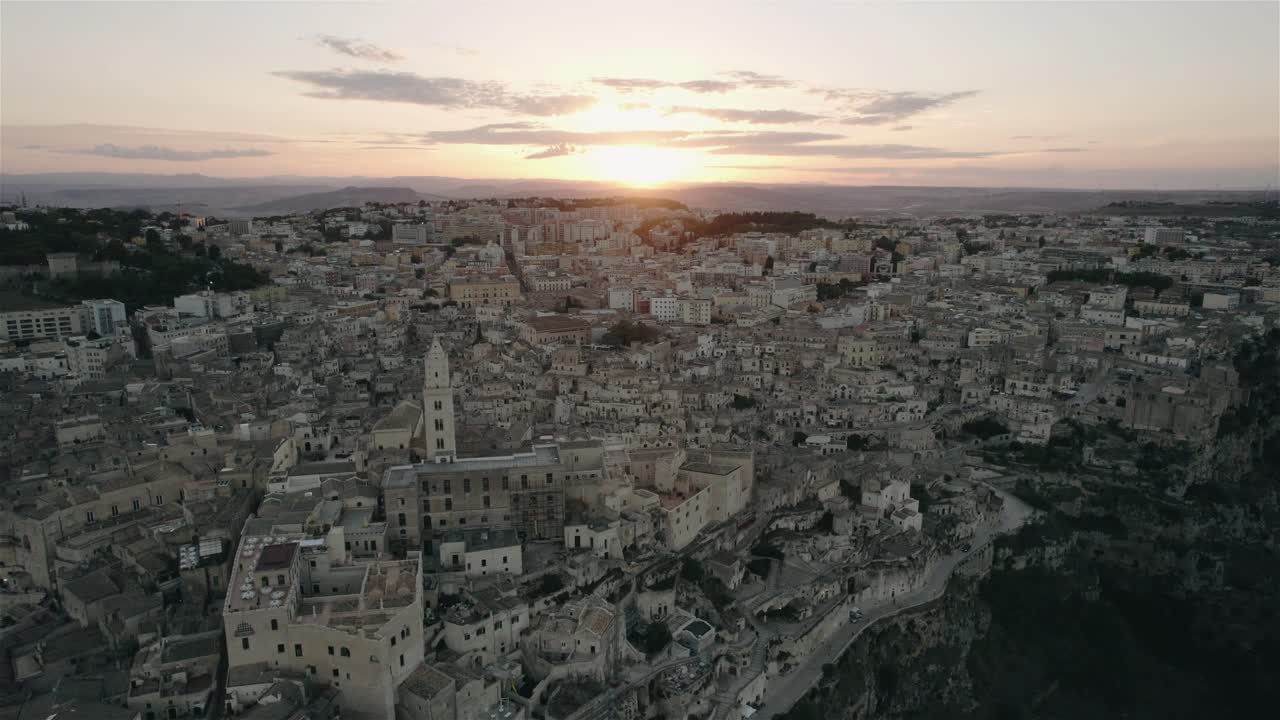 Dron lecący w stronę starego białego miasta Matera o zachodzie słońca w południowych Włoszech w 4k