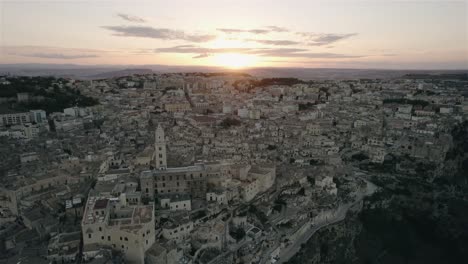 Drone-Volando-Hacia-La-Antigua-Ciudad-Blanca-De-Matera-Al-Atardecer-En-El-Sur-De-Italia-En-4k