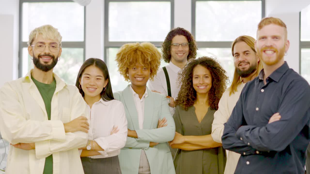 Coworkers standing with arms crossed smiling at camera together