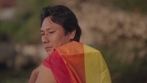 man with rainbow flag at sunset
