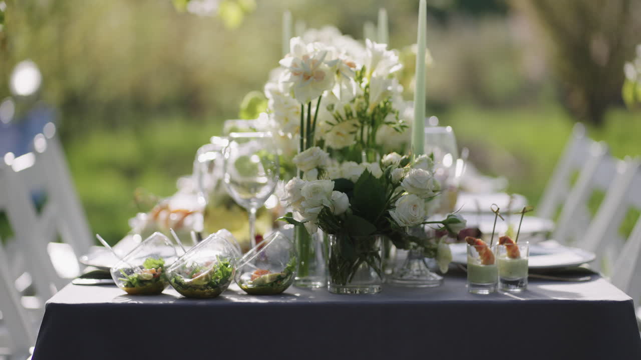 Smuk blomsterudsmykning og lækre forretter på et bord i en blomstrende have om foråret, nærbillede.