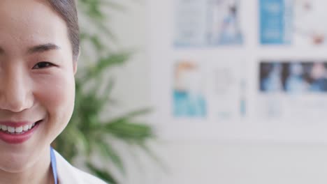 Half-face-video-portrait-of-happy-asian-female-doctor-smiling-in-hospital-corridor,-with-copy-space