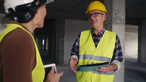 Ingenieros-Caucásicos-Masculinos-Y-Femeninos-Hablando-En-El-Sitio-De-Construcción.