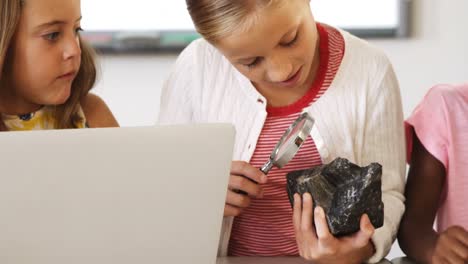 niños de la escuela usando lupa sobre la roca