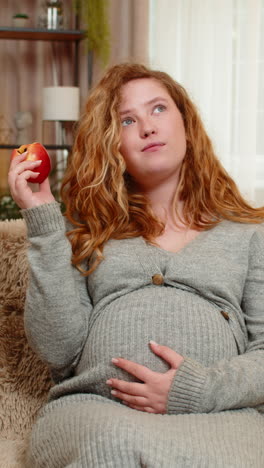 pregnant woman eating apple gently touching belly relaxed with calm expression and healthy glow