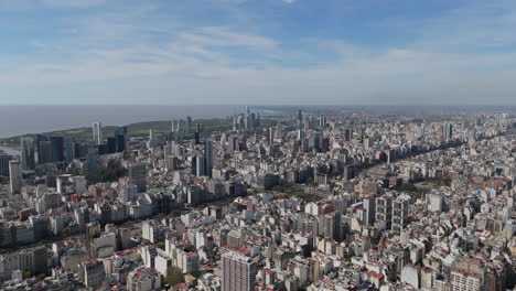 Aerial pan shot of the cityscape Buenos Aires, the coast in the background, nice day with few clouds, copy space